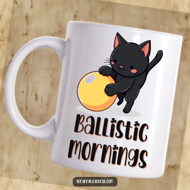Funny cat mug showing a black cat in mid-pounce towards a bright, bouncy ball, full of playful energy.
