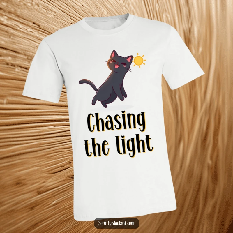 Funny t-shirt showing a black cat ecstatically chasing a bright, dancing sunbeam across the floor, embodying pure joy.
