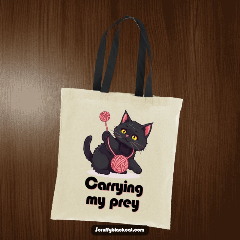 Funny Tote Bag: Scruffy black cat playfully batting at a dangling yarn ball, a humorous and practical accessory for cat lovers.