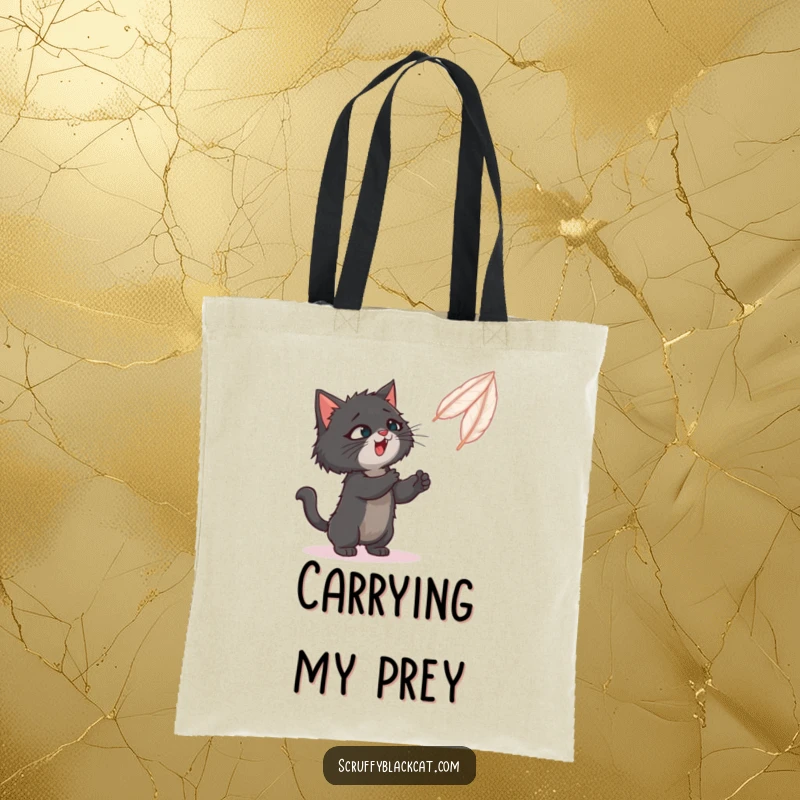 Funny tote bag showing a scruffy black cat playfully batting at a bouncing feather toy.