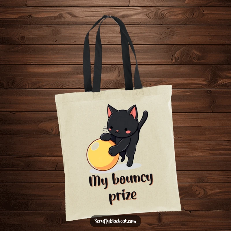 Funny cat tote bag showing a black cat in a playful pounce over a bright, bouncy ball, highlighting active fun.
