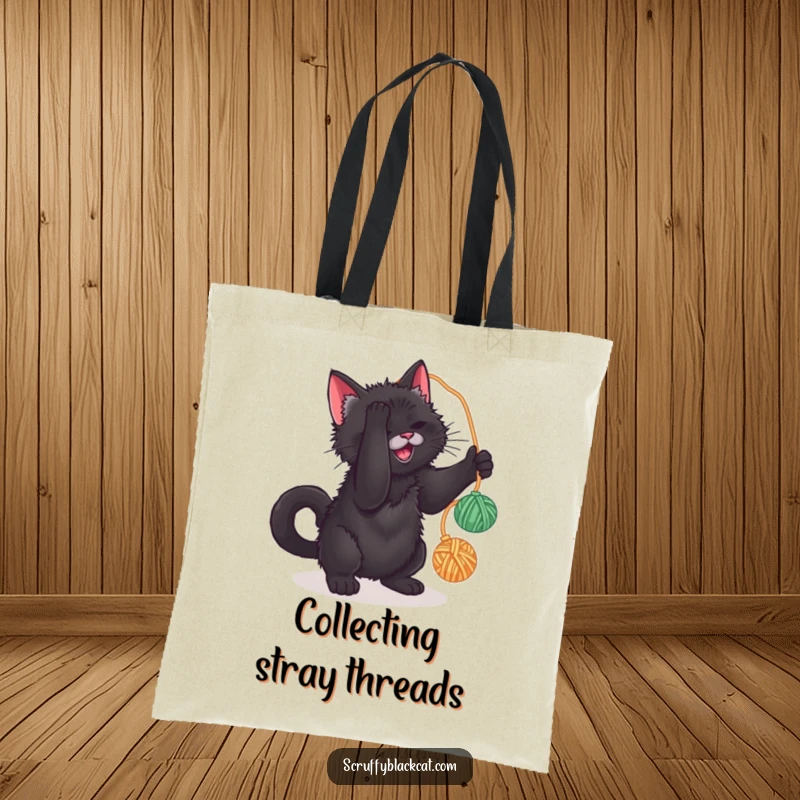 Funny tote bag featuring a scruffy black cat batting at a yarn ball, perfect for carrying items with feline flair.