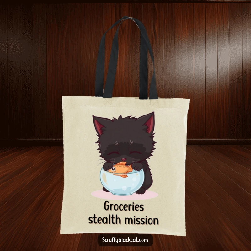 Funny black kitten tote bag, illustrated gently reaching for a fish in a tiny bowl, embodying quiet determination.